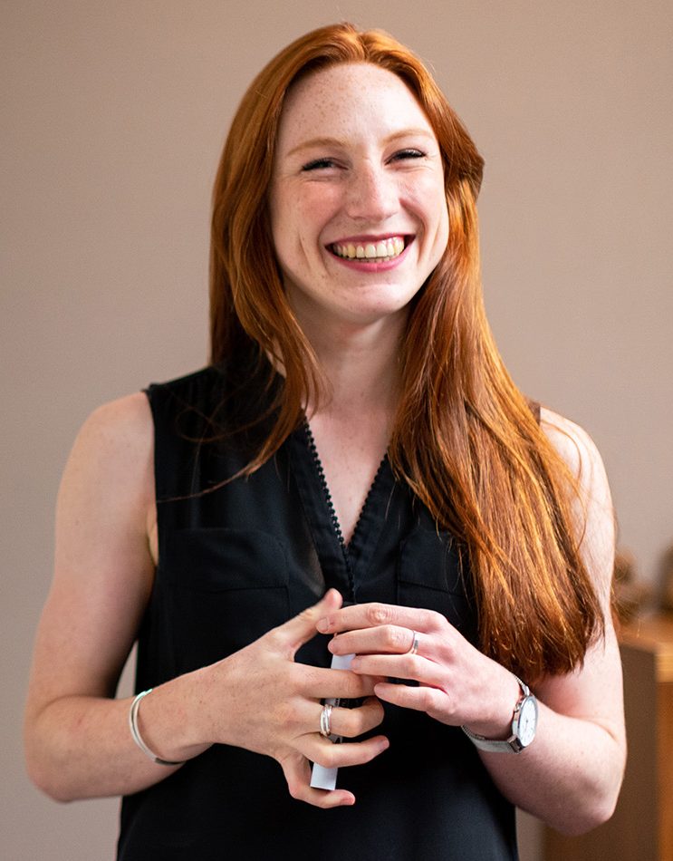 Smiling office administrator standing in a modern office, symbolizing a welcoming and professional front office role.