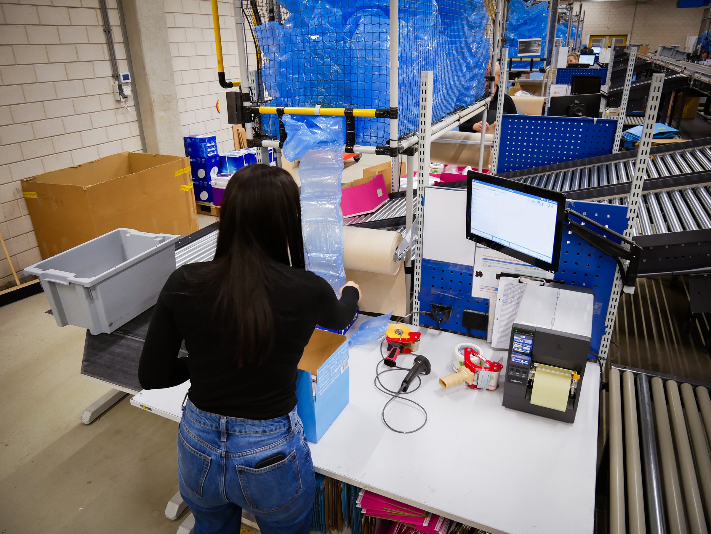 E-commerce order picker packing items at the white desk. Work with scanner.