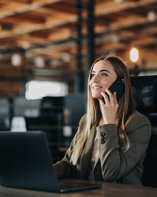 Planner speaking on the phone while managing schedules and workforce planning at a desk in a modern office.